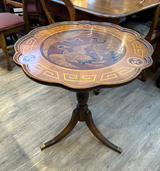 Round scalloped edge tilt top table with inlaid wood stork bird image pattern