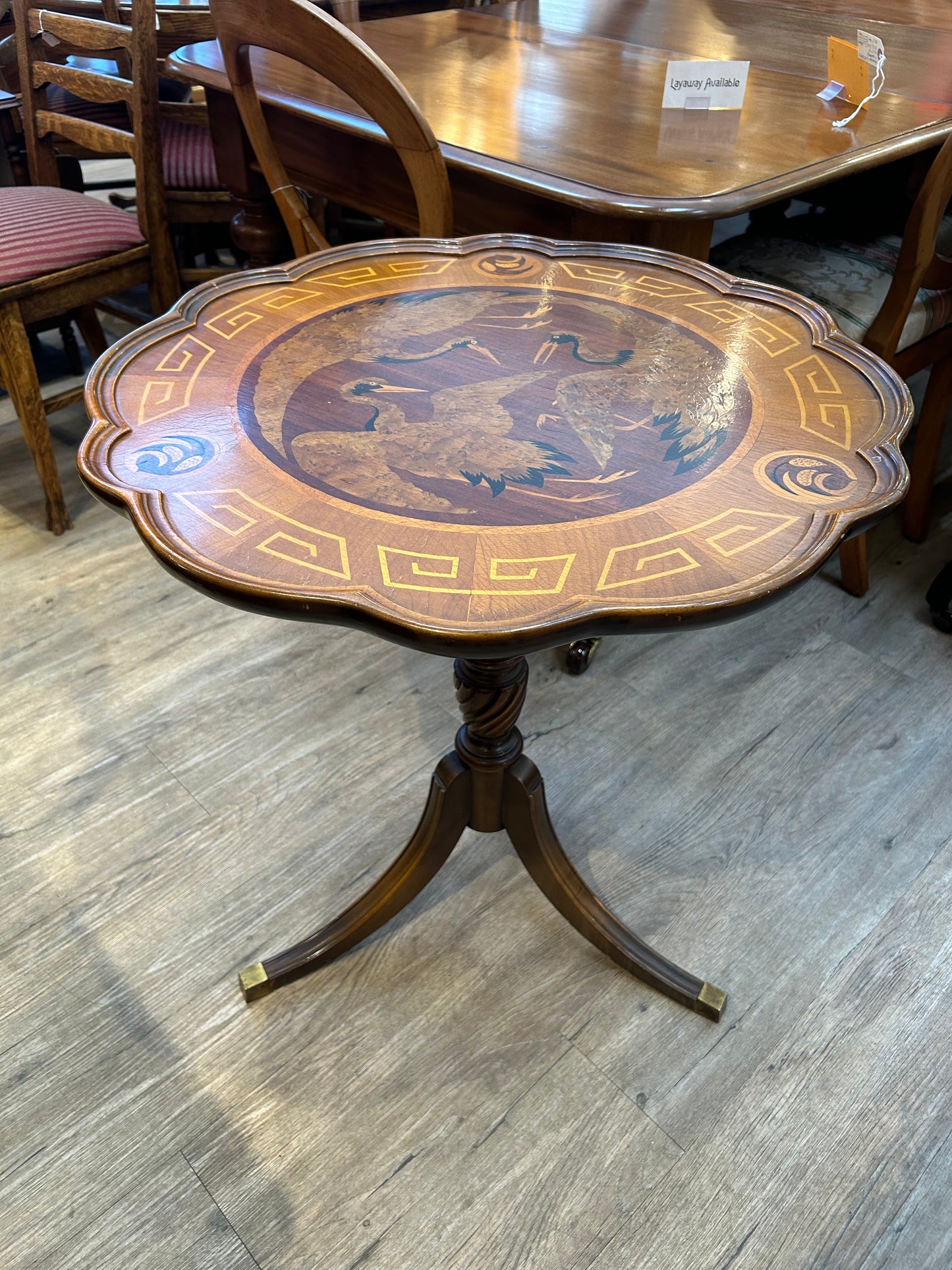 Round scalloped edge tilt top table with inlaid wood stork bird image pattern